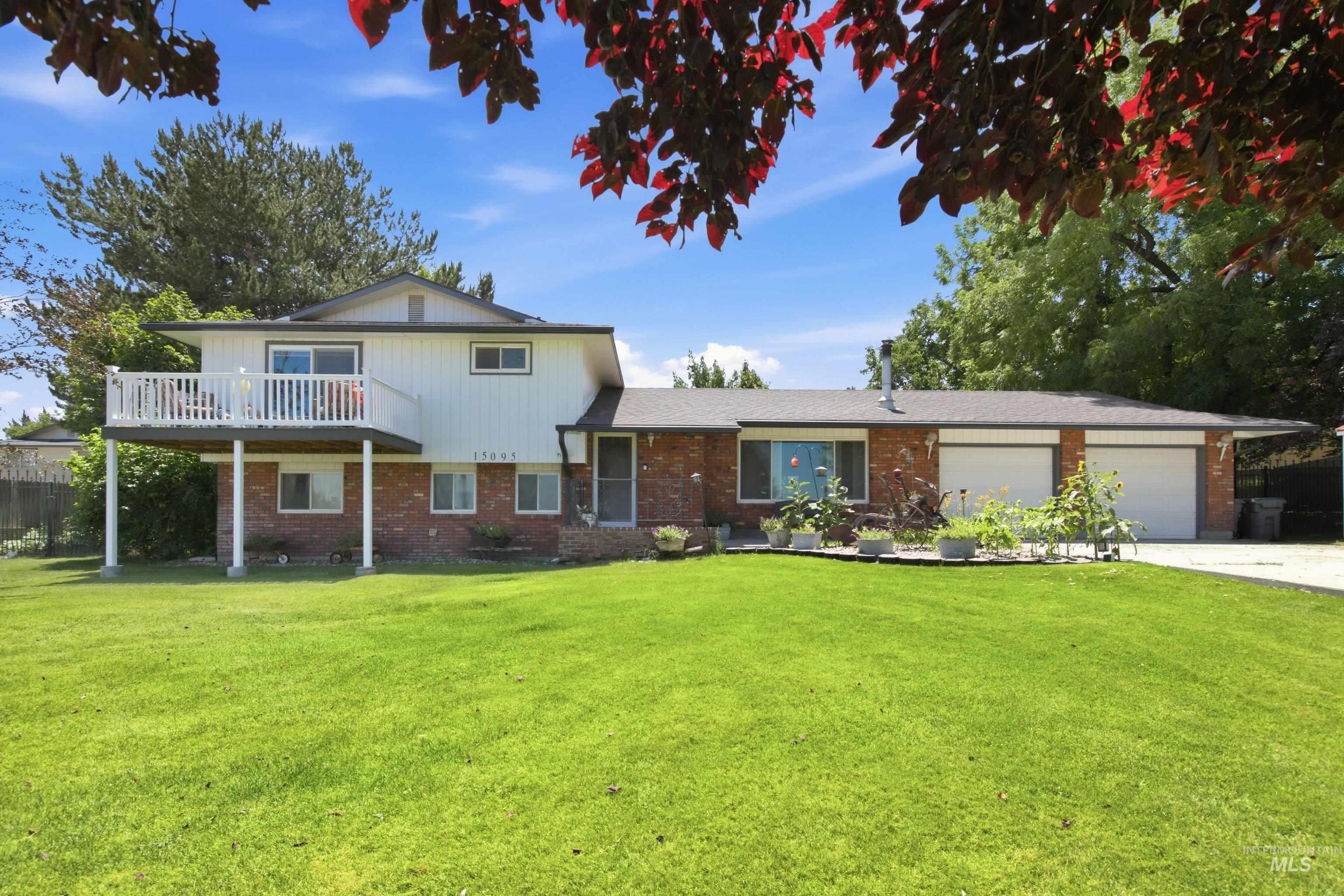 15095 David Street Caldwell, ID 83607 - Photo 2 of 39 Two-story residence featuring a brick and white siding exterior, an upper-level balcony with white railings, a front lawn, and a two-car garage