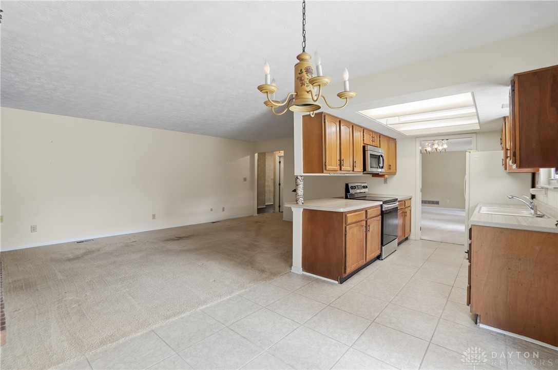 9964 Hummingbird Way Dayton, OH 45458 - Photo 23 of 57 This bright kitchen with ample cabinetry transitions seamlessly into the carpeted living space.