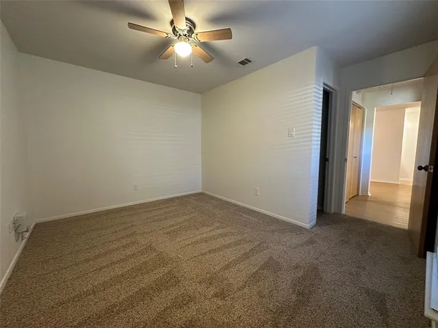 an empty room with closet and a ceiling fan