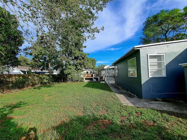 a view of a backyard with potted plants and large trees