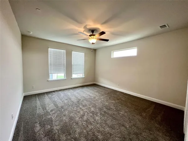 an empty room with windows and ceiling fan