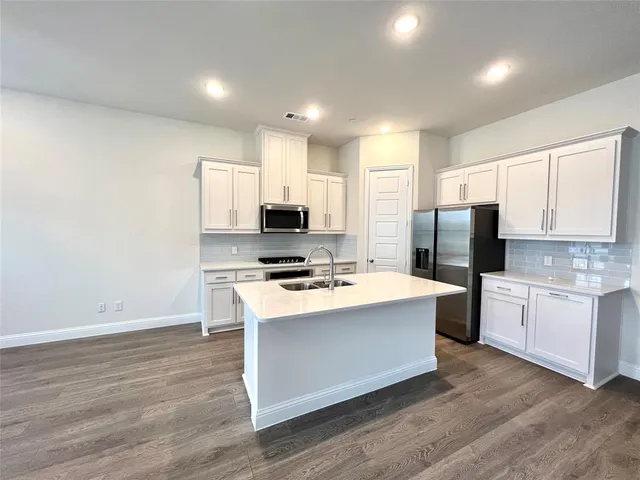 a large kitchen with kitchen island a sink a stove a refrigerator and white cabinets