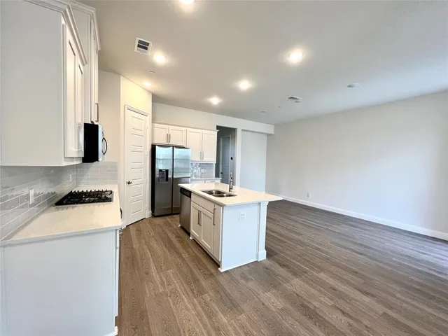 a large kitchen with stainless steel appliances granite countertop a stove a sink and a refrigerator