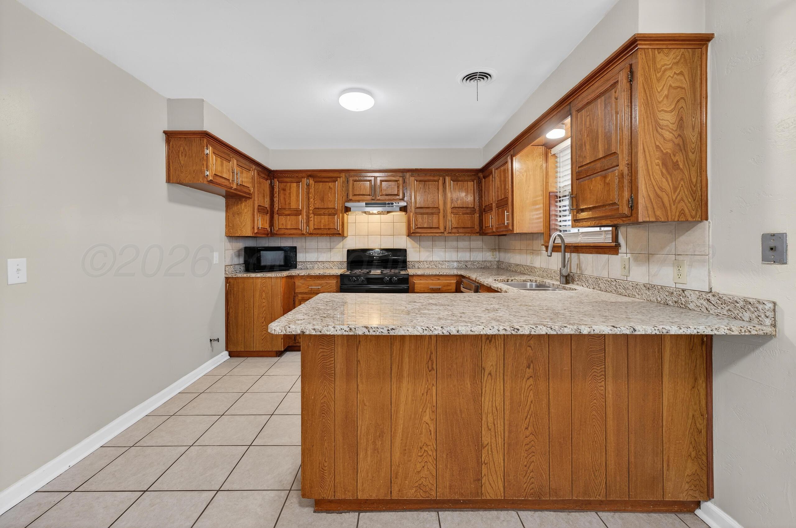 7313 Holyoke Trail Amarillo, TX 79121 - Photo 16 of 56 a kitchen with granite countertop a sink a stove cabinets and counter space