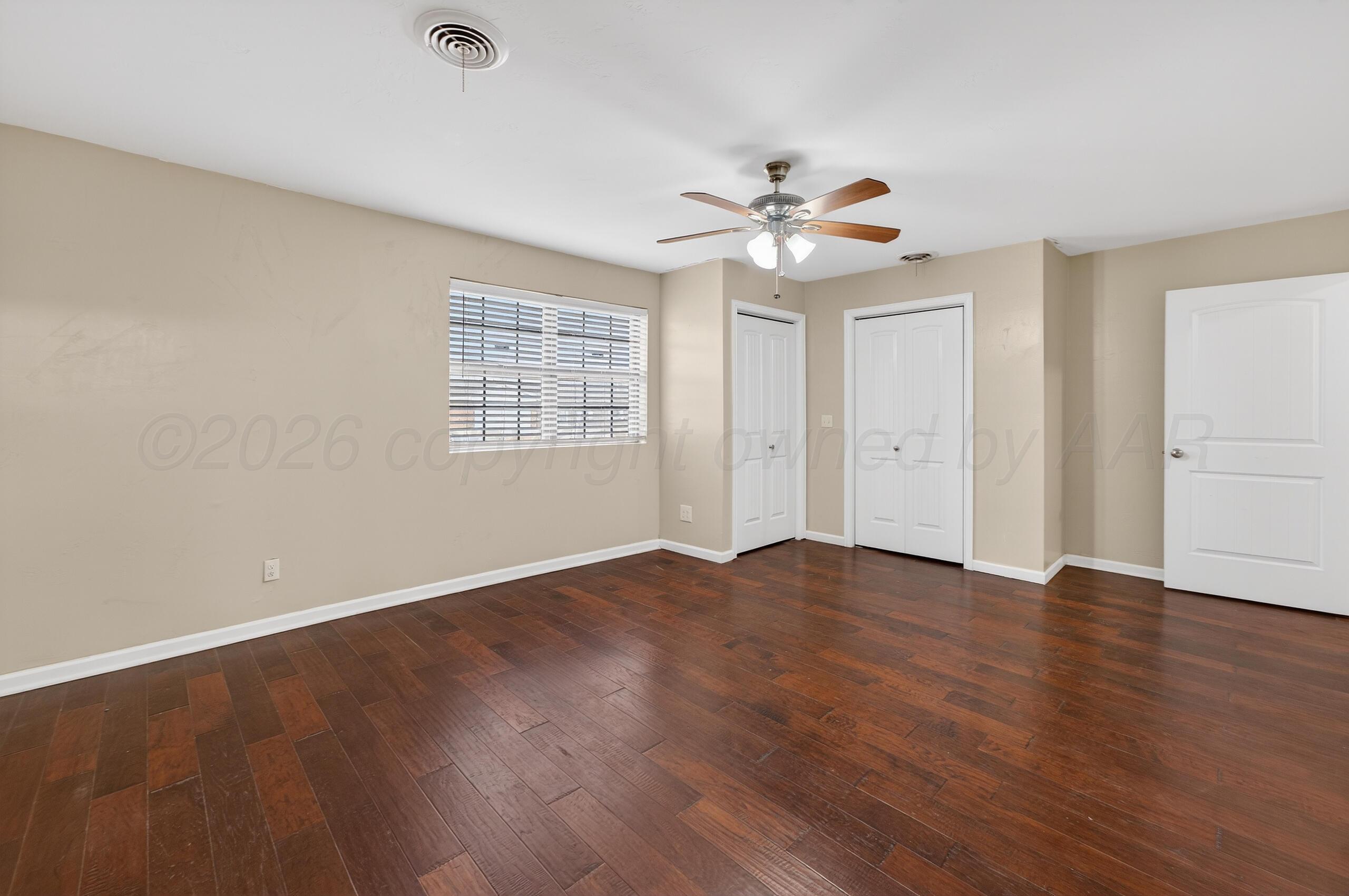 7313 Holyoke Trail Amarillo, TX 79121 - Photo 28 of 56 an empty room with wooden floor chandelier fan and windows