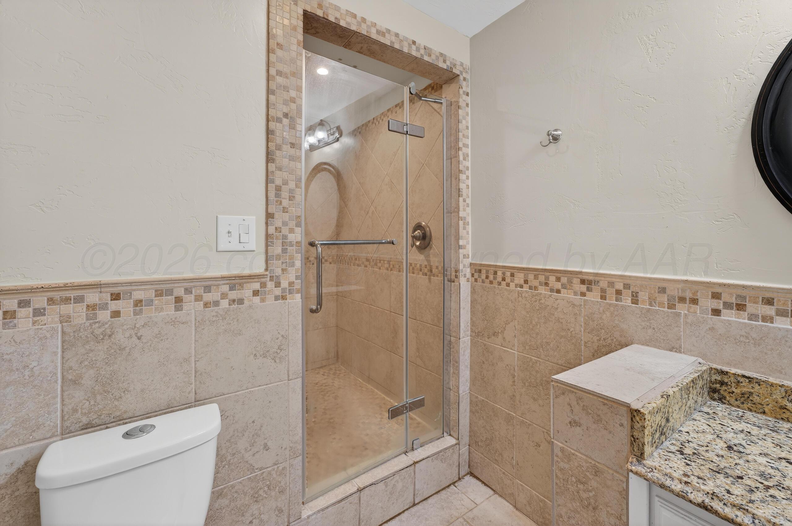 7313 Holyoke Trail Amarillo, TX 79121 - Photo 34 of 56 a bathroom with a granite countertop shower a toilet and a sink