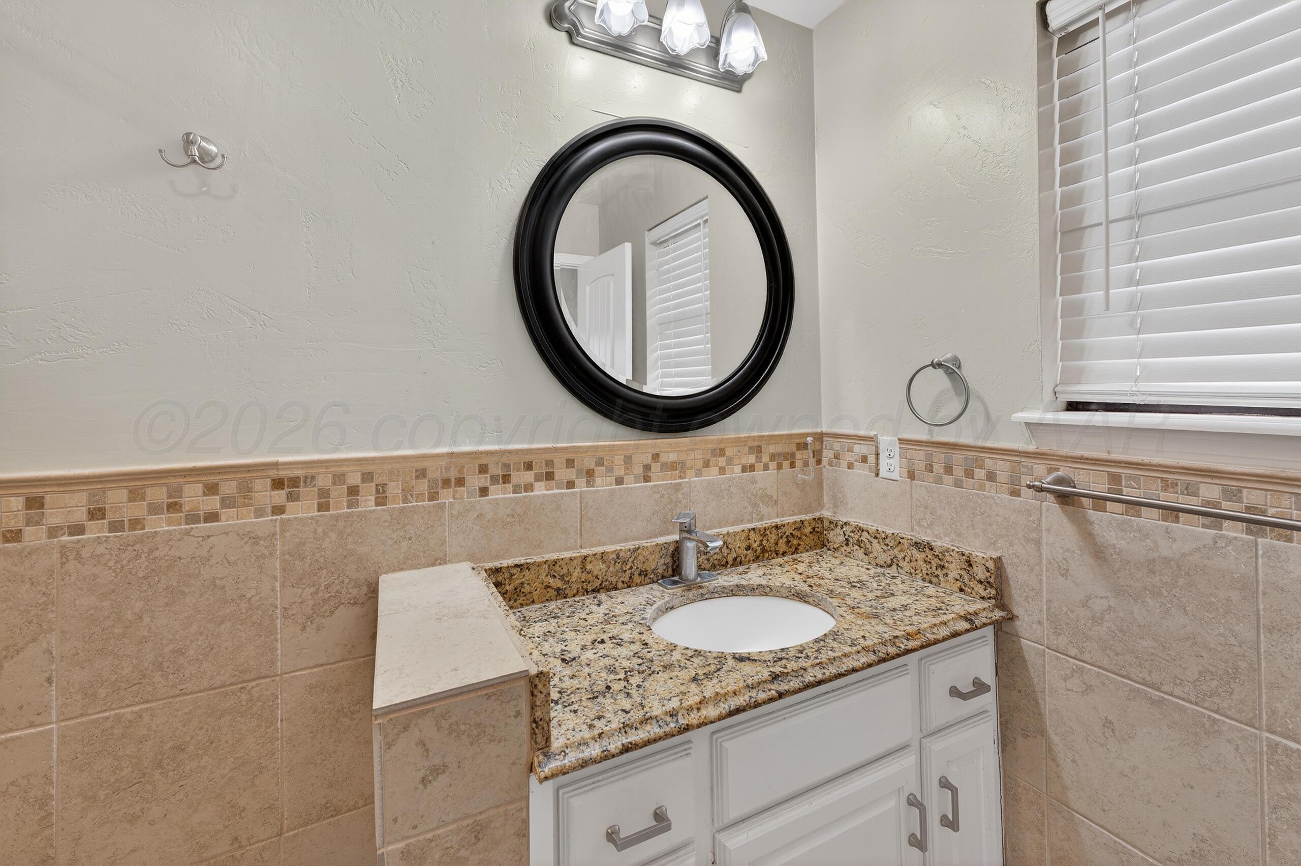 7313 Holyoke Trail Amarillo, TX 79121 - Photo 36 of 56 a bathroom with a granite countertop sink a mirror and a shower
