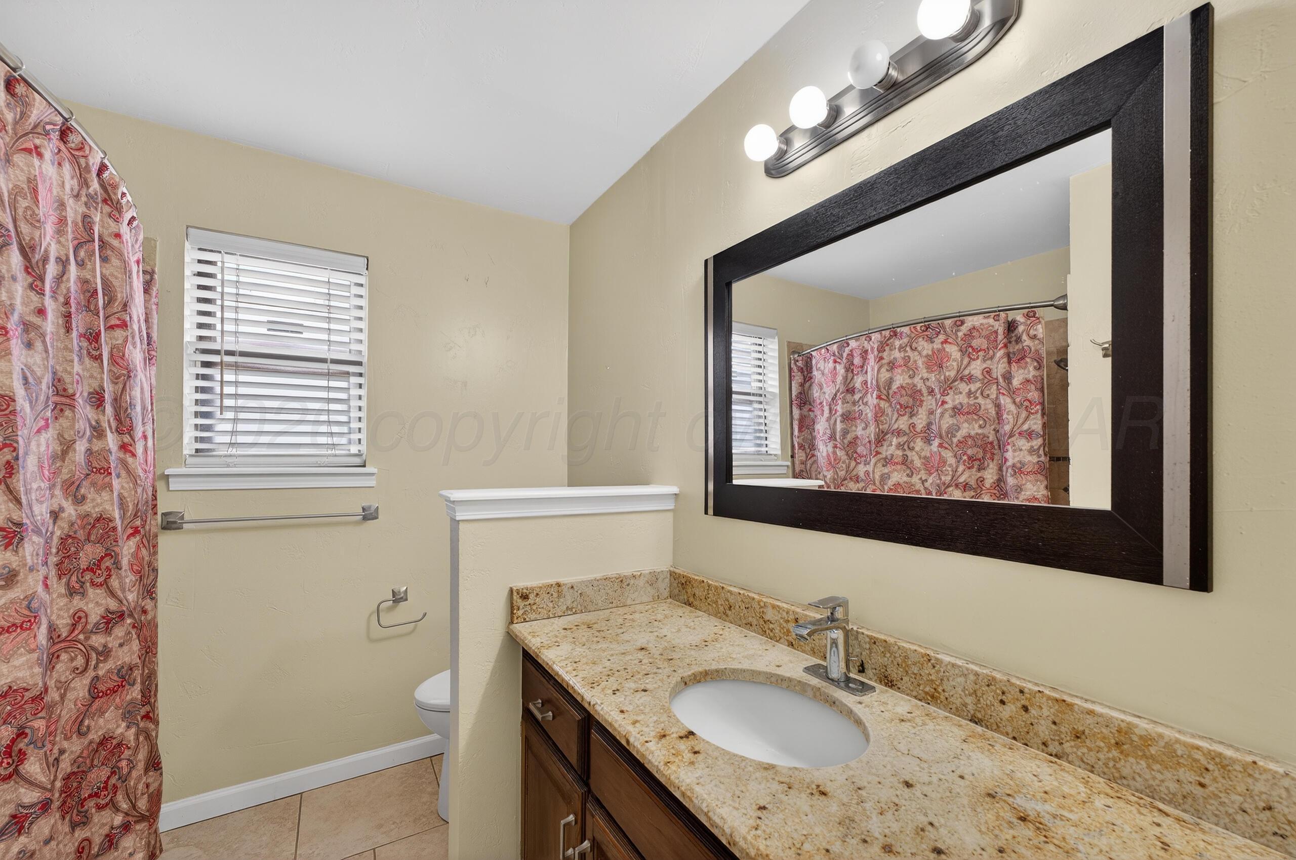7313 Holyoke Trail Amarillo, TX 79121 - Photo 44 of 56 a bathroom with a granite countertop sink a vanity and a mirror