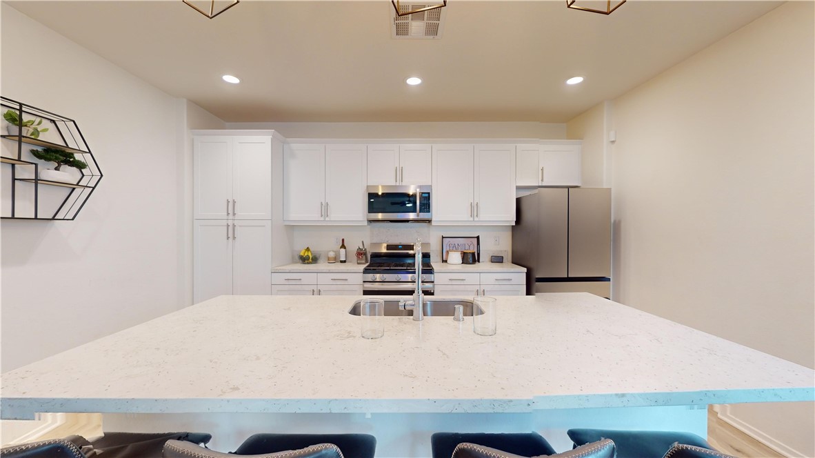 165 Linden Court Perris, CA 92571 - Photo 5 of 36 a kitchen with a refrigerator a stove and a sink with wooden floor