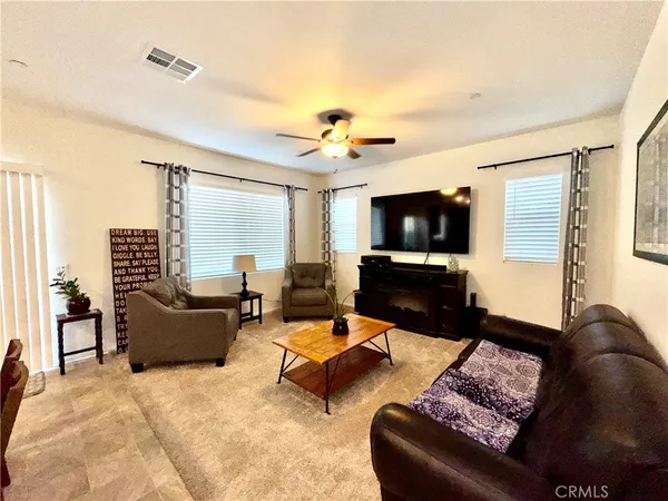 a living room with furniture ceiling fan and a flat screen tv