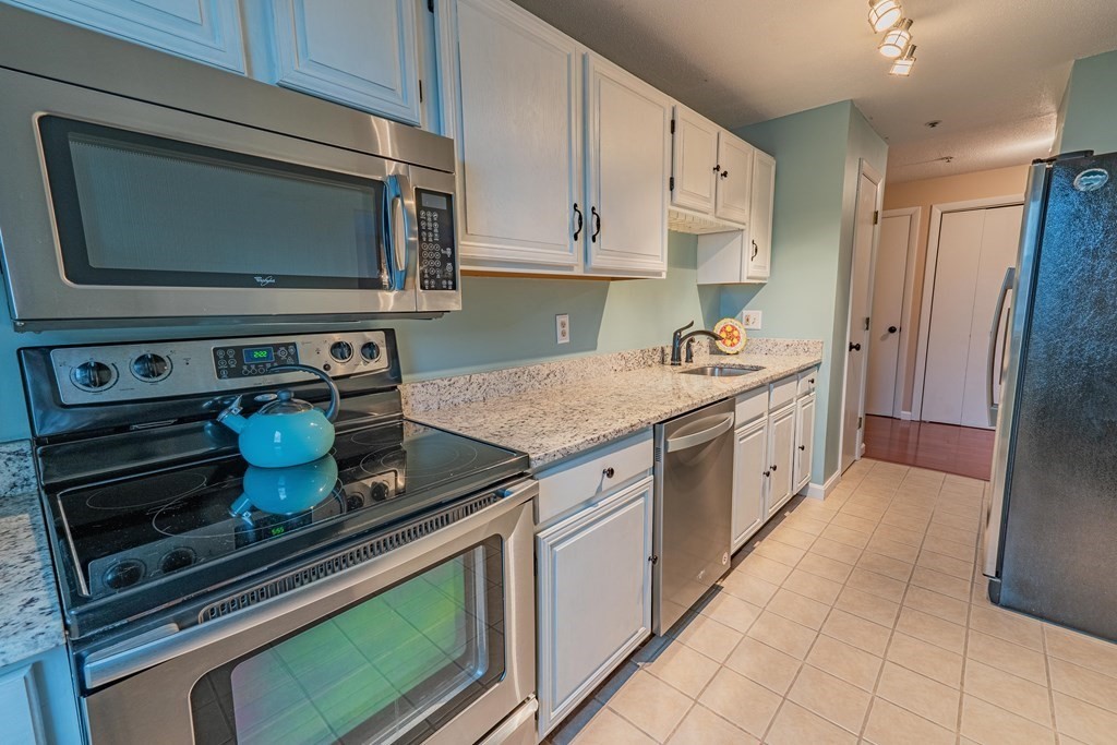 38 Dunham Road, Unit 210 Beverly, MA 01915 - Photo 11 of 30 a kitchen with stainless steel appliances granite countertop a sink and a stove