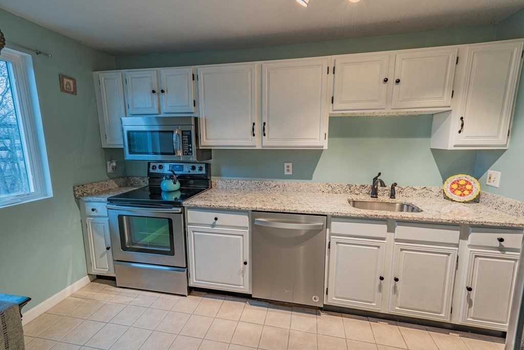 38 Dunham Road, Unit 210 Beverly, MA 01915 - Photo 13 of 30 a kitchen with granite countertop white cabinets and white appliances