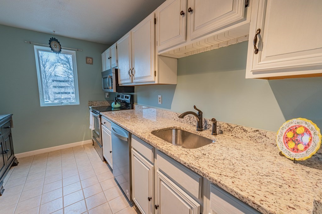 38 Dunham Road, Unit 210 Beverly, MA 01915 - Photo 14 of 30 a kitchen with granite countertop a sink a stove and cabinets