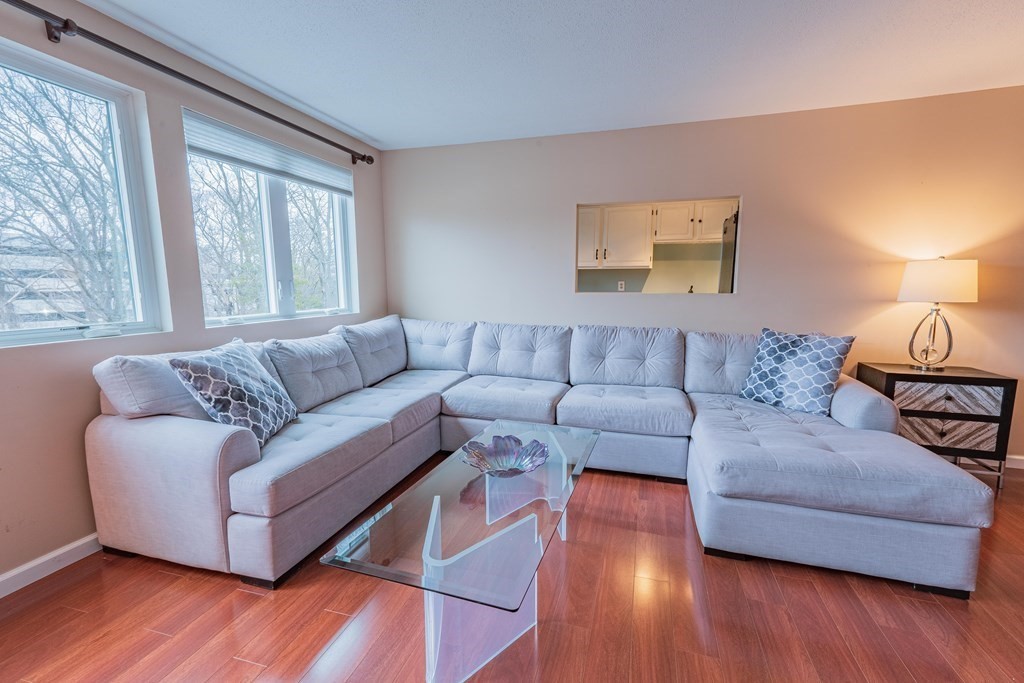 38 Dunham Road, Unit 210 Beverly, MA 01915 - Photo 6 of 30 a living room with couches and a large window with wooden floor