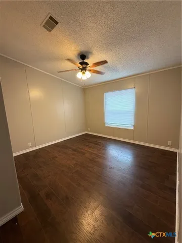 an empty room with wooden floor and fan