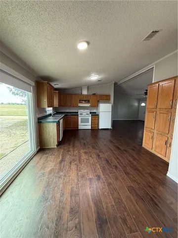 a view of a kitchen with a sink and dishwasher a stove top oven with wooden floor