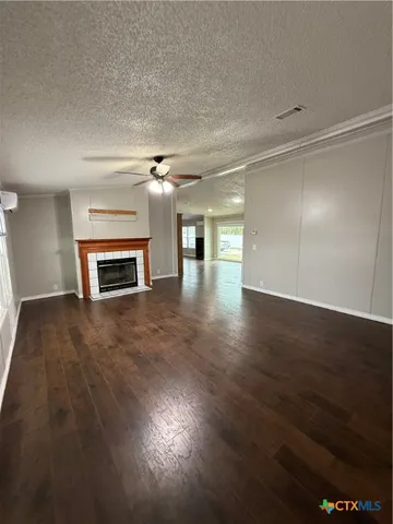 an empty room with wooden floor fireplace and windows