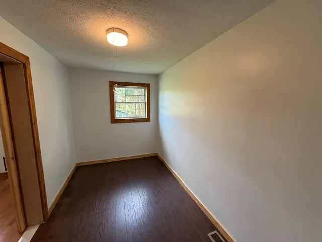 a view of a big room with wooden floor and windows