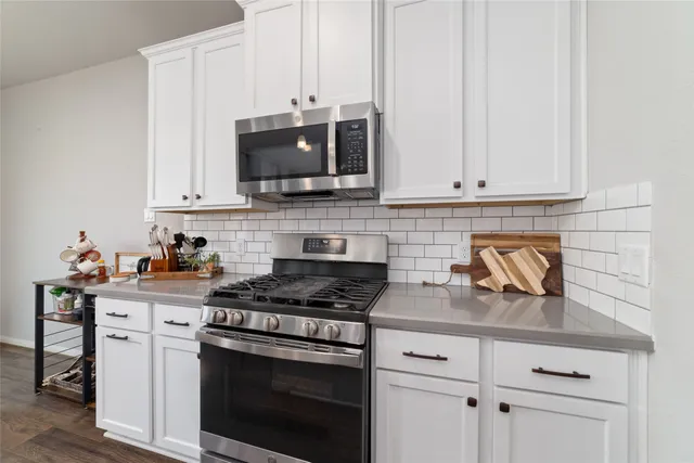 a kitchen with stainless steel appliances granite countertop white cabinets a stove a sink and dishwasher