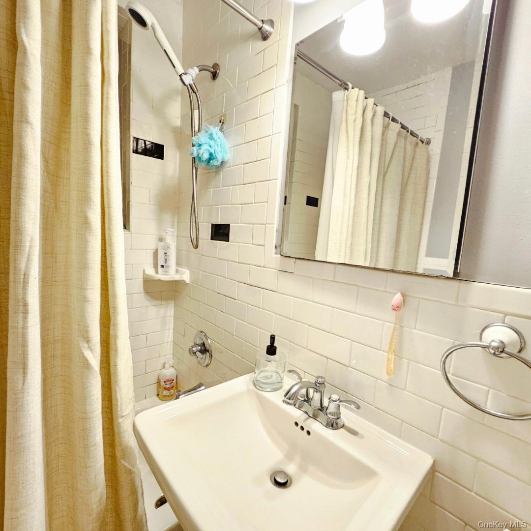 215-43 48th Avenue, Unit 3B Queens, NY 11364 - Photo 12 of 14 a bathroom with a sink a mirror a vanity and a shower