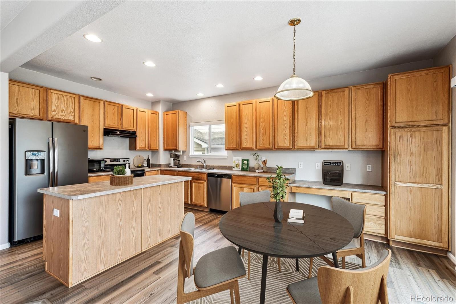 6485 Silverleaf Avenue Firestone, CO 80504 - Photo 5 of 29 a kitchen with a refrigerator a stove a sink dishwasher with a dining table and chairs