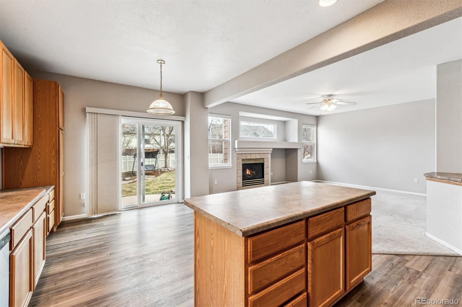 6485 Silverleaf Avenue Firestone, CO 80504 - Photo 9 of 29 a kitchen with a center island wooden floor and a fireplace