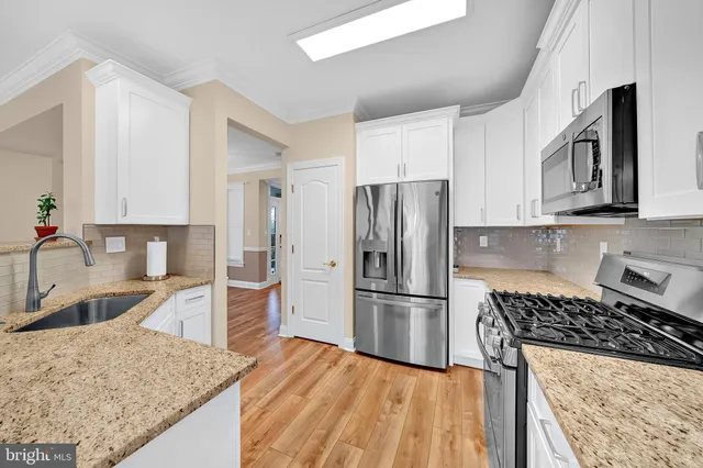 a kitchen with granite countertop a refrigerator stove and sink