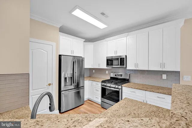 a kitchen with granite countertop a refrigerator and a stove top oven