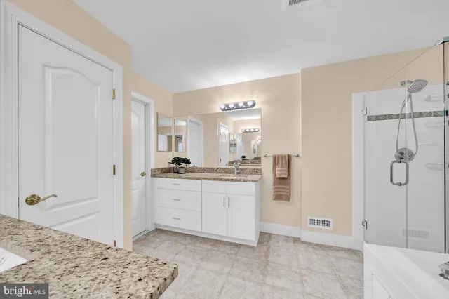 a bathroom with a granite countertop sink a mirror and a bathtub