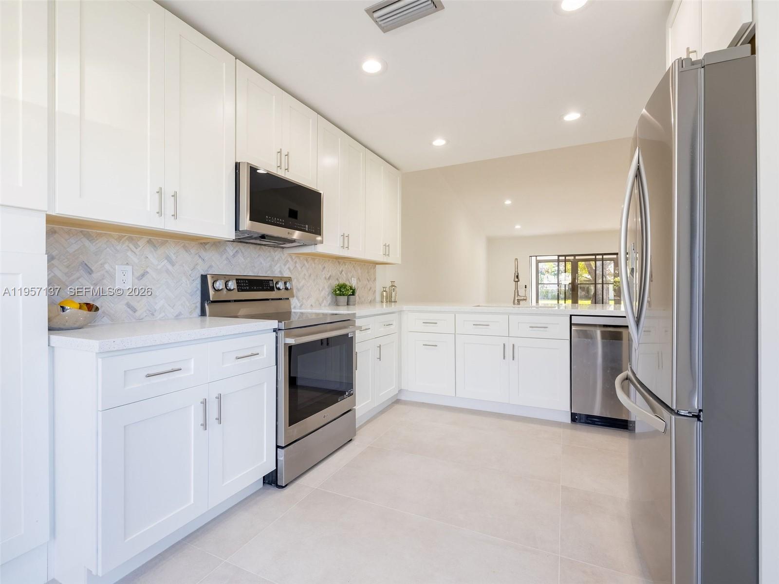10988 Lake Front Place Boca Raton, FL 33498 - Photo 8 of 85 a kitchen with white cabinets and white appliances