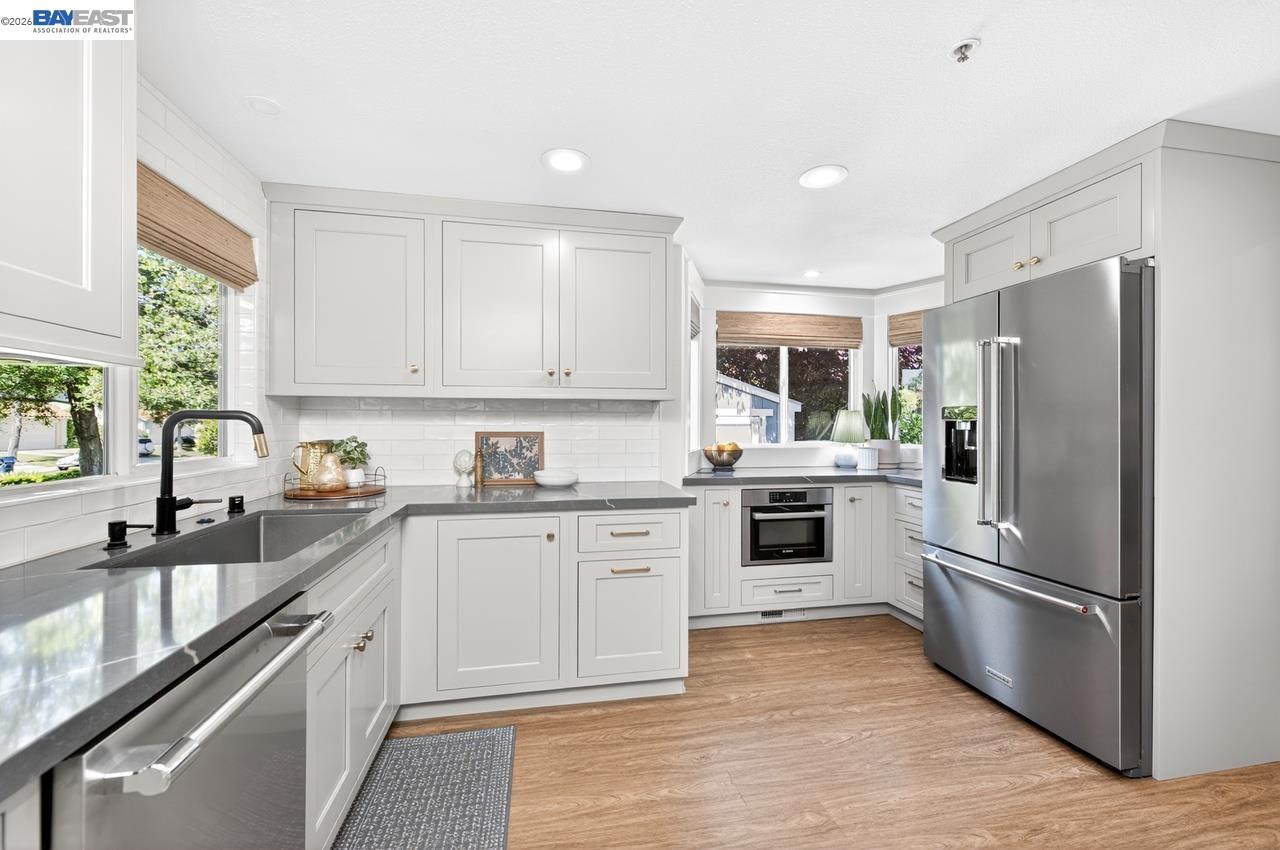 308 Mulqueeney Street Livermore, CA 94550 - Photo 14 of 51 a kitchen with granite countertop a refrigerator oven a sink dishwasher and white cabinets with wooden floor