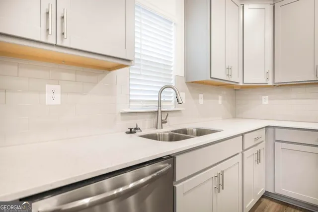 a kitchen with stainless steel appliances granite countertop white cabinets and a sink