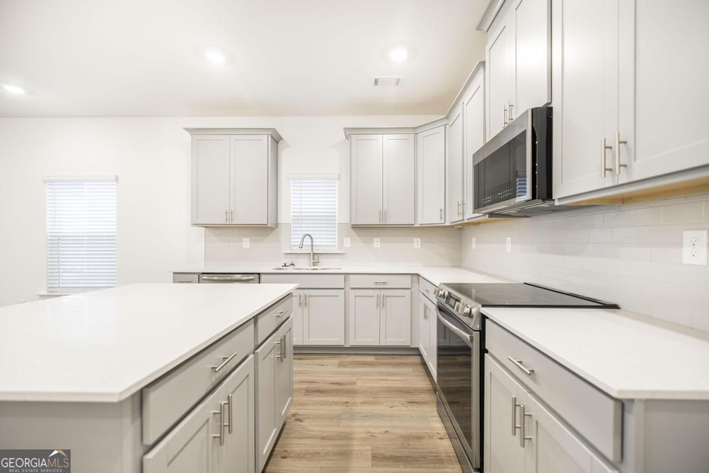 108 Palmetto Avenue Perry, GA 31069 - Photo 10 of 30 a kitchen with stainless steel appliances granite countertop a sink and dishwasher a stove top oven with white cabinets