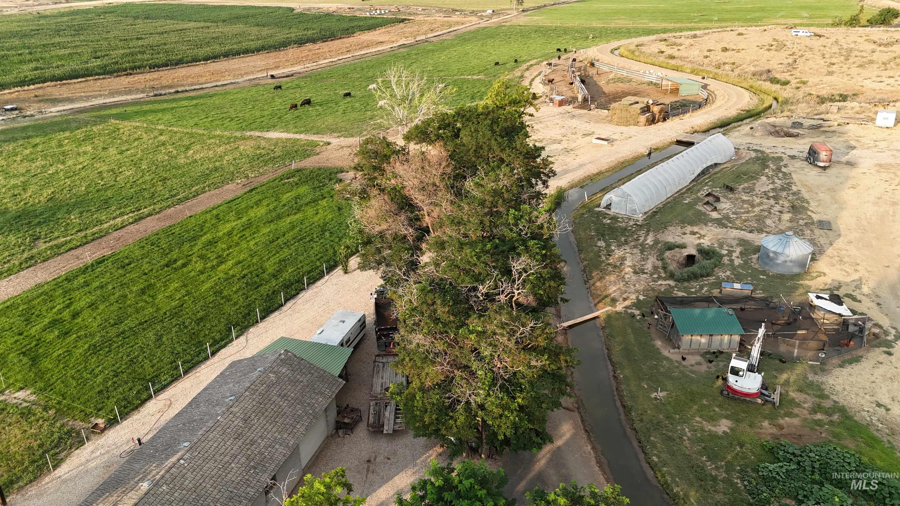 6712 Stage Coach Road Nampa, ID 83686 - Photo 25 of 48 Expansive aerial view showcasing a single-family residence with a gray shingle roof, a barn with a green metal roof, and surrounding cultivated land