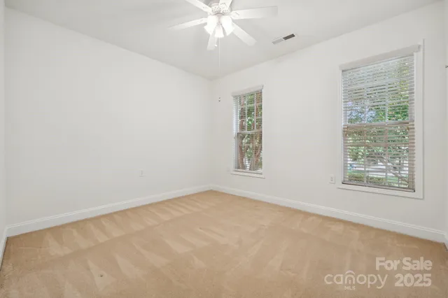 an empty room with windows and fan