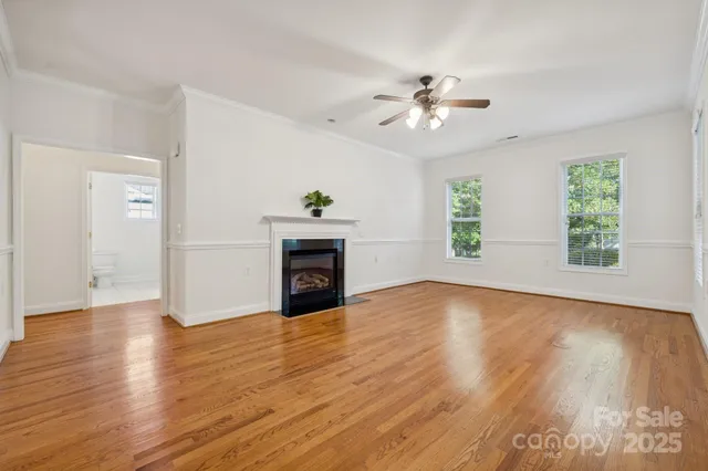 an empty room with windows fireplace and wooden floor