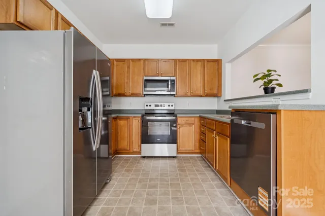 a kitchen with stainless steel appliances granite countertop a refrigerator and a stove top oven
