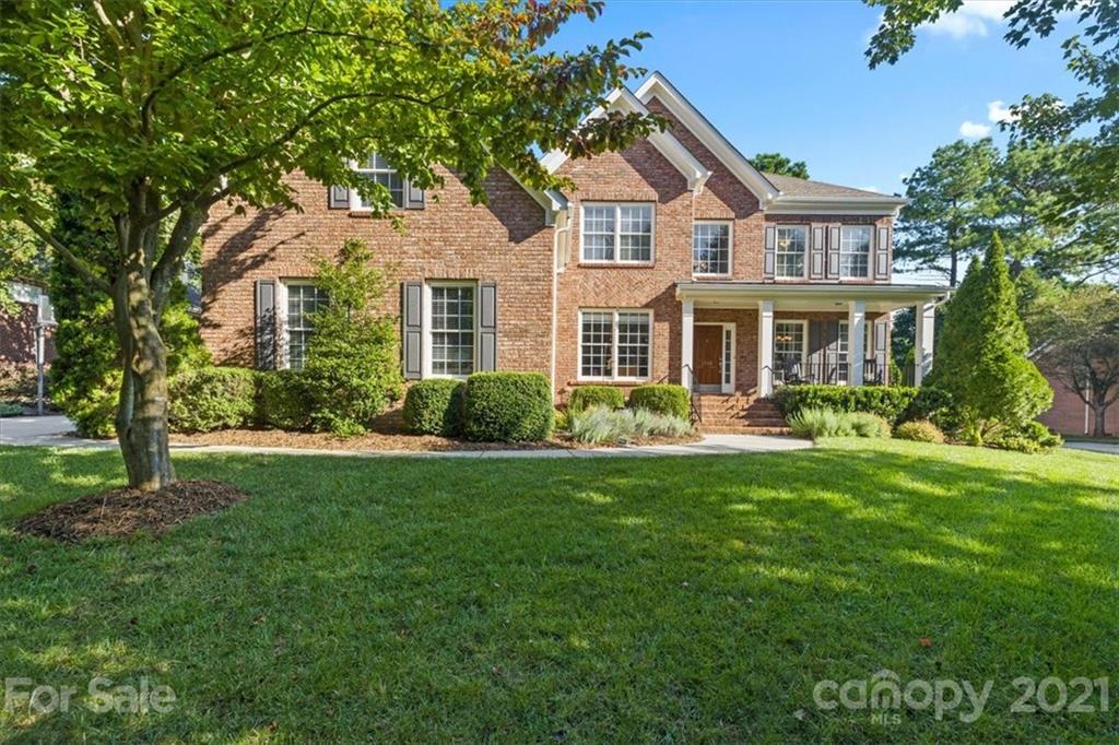 a front view of a house with a garden and trees