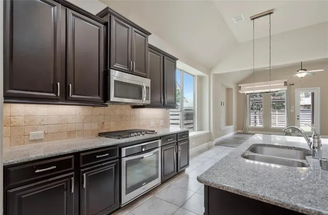 a kitchen with granite countertop stainless steel appliances a stove sink and microwave