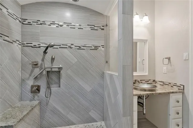 a bathroom with a granite countertop sink a mirror and shower