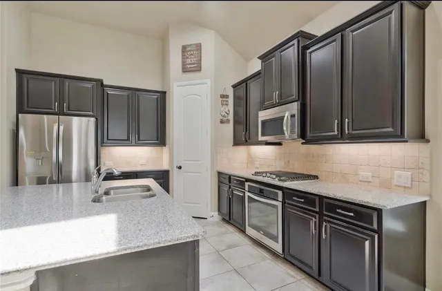 a kitchen with stainless steel appliances granite countertop a sink stove and refrigerator