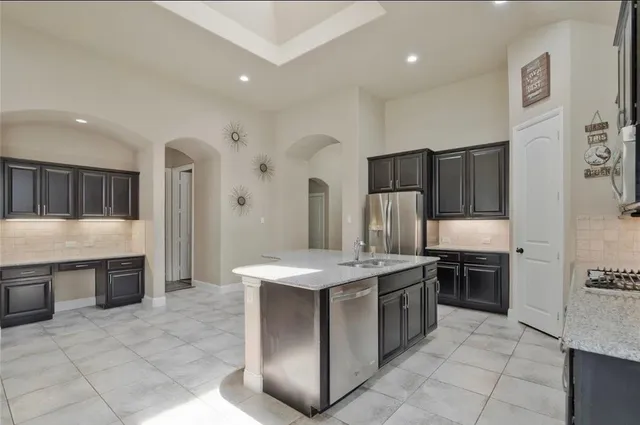 a kitchen with stainless steel appliances granite countertop a stove a sink and a refrigerator