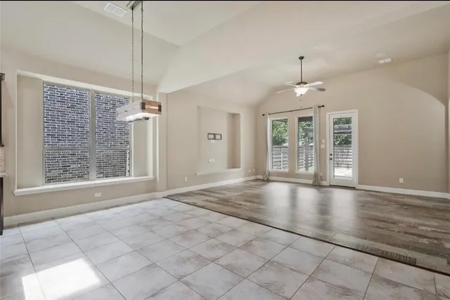 a view of an empty room with window and chandelier fan