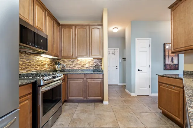 a kitchen with stainless steel appliances granite countertop a stove a sink and a refrigerator