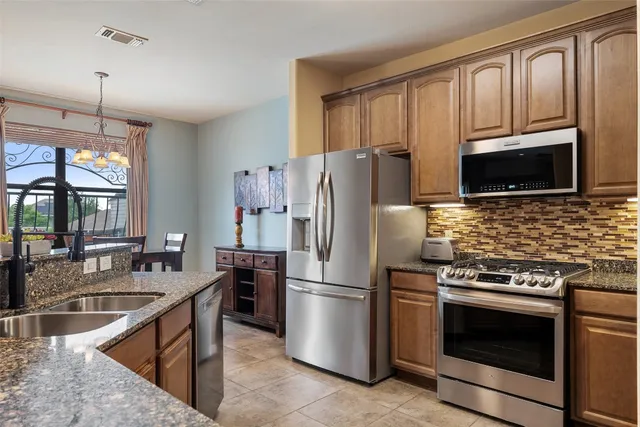 a kitchen with granite countertop a sink stove and refrigerator