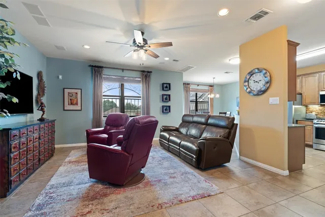 a living room with furniture a ceiling fan and a large window