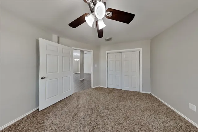 a view of an empty room and chandelier fan