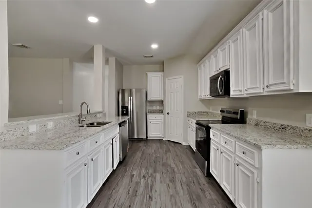 a kitchen with granite countertop a sink stove cabinets and refrigerator
