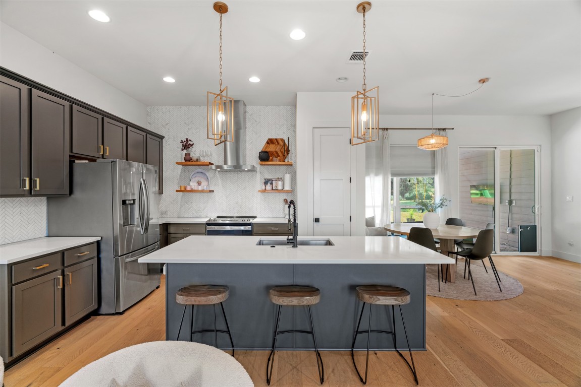 330 Kendall Road Spicewood, TX 78669 - Photo 4 of 32 a kitchen with stainless steel appliances a dining table chairs stove refrigerator and cabinets