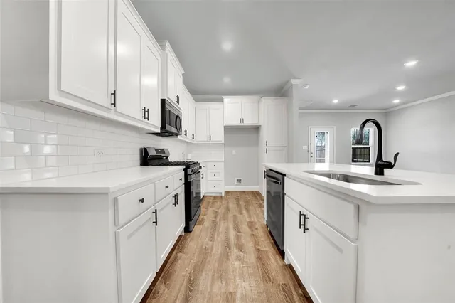 a kitchen with white cabinets appliances and a sink